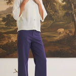 Model wearing graced navy wide-leg Darcy pants with pocket details and a white button-up cardigan