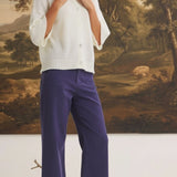 Model wearing graced navy wide-leg Darcy pants with pocket details and a white button-up cardigan