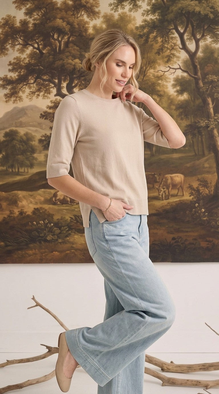 graced oatmeal short sleeve knit top worn by a woman with light blue jeans in a studio setting
