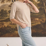 graced oatmeal short sleeve knit top worn by a woman with light blue jeans in a studio setting