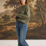 graced chunky olive green crewneck sweater worn by a woman with blue jeans and white sneakers