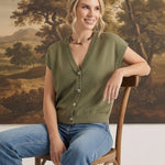 graced olive sleeveless button-down cotton top worn by a smiling model with blue jeans in a studio setting