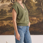 graced olive green sleeveless cotton button-down top worn by a model with blue jeans in a studio setting
