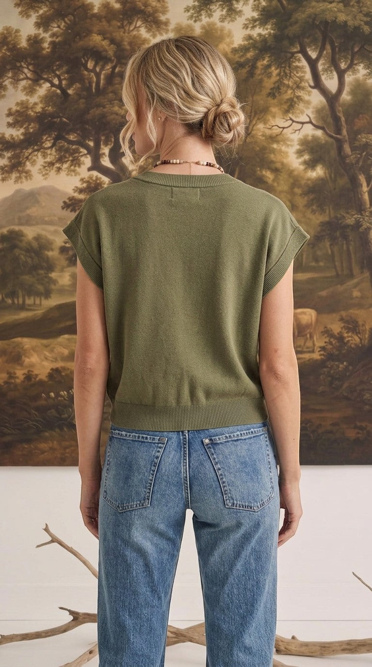 Back view of a woman wearing a graced olive green sleeveless cotton button-down top paired with blue jeans.