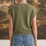 Back view of a woman wearing a graced olive green sleeveless cotton button-down top paired with blue jeans.