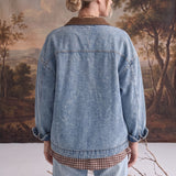 Back view of a woman wearing a graced oversized blue denim jacket with a brown corduroy collar and latch hook closure