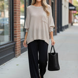 Model wearing a graced pebble dolman long sleeve knit sweater with a chest pocket and relaxed fit on a city street.