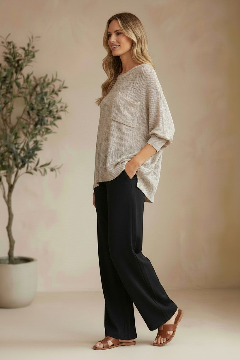 graced pebble dolman long sleeve knit sweater with pocket detail worn by a model with black trousers and sandals