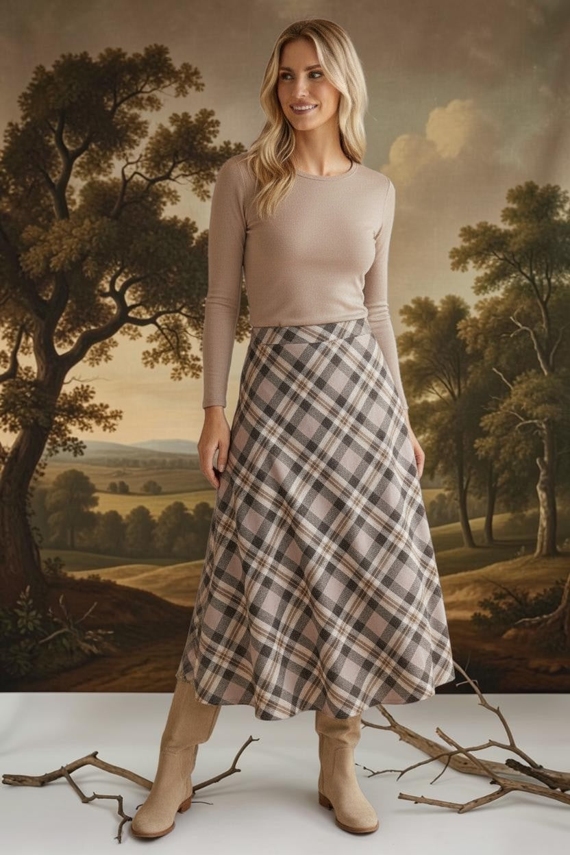 Model wearing a graced A-line midi skirt in a beige and brown plaid pattern with a long-sleeve top and suede boots.