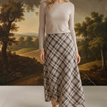graced A-line midi skirt in a beige and black plaid pattern worn with a long-sleeve top and suede boots