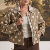 Model wearing a graced Julia polka dot canvas twill jacket in tan with a gingham collar, styled over a white top.