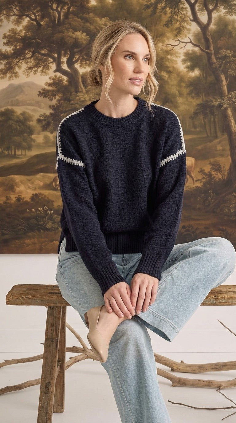graced The Sheila Sweater in navy blue with white crochet shoulder detailing, worn by a model with light jeans.