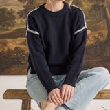 graced The Sheila Sweater in navy blue with white crochet shoulder detailing, worn by a model with light jeans.