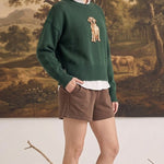 graced model wearing a dark green Sydney Retriever sweater with a dog graphic over a white shirt and brown shorts