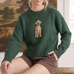 graced Sydney Retriever sweater in dark green with a golden retriever knit design, worn by a woman on a wooden bench