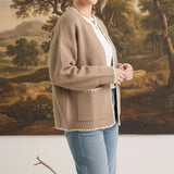 Model wearing a graced tan open-front cardigan with white contrast stitching and pockets over a white top and jeans.