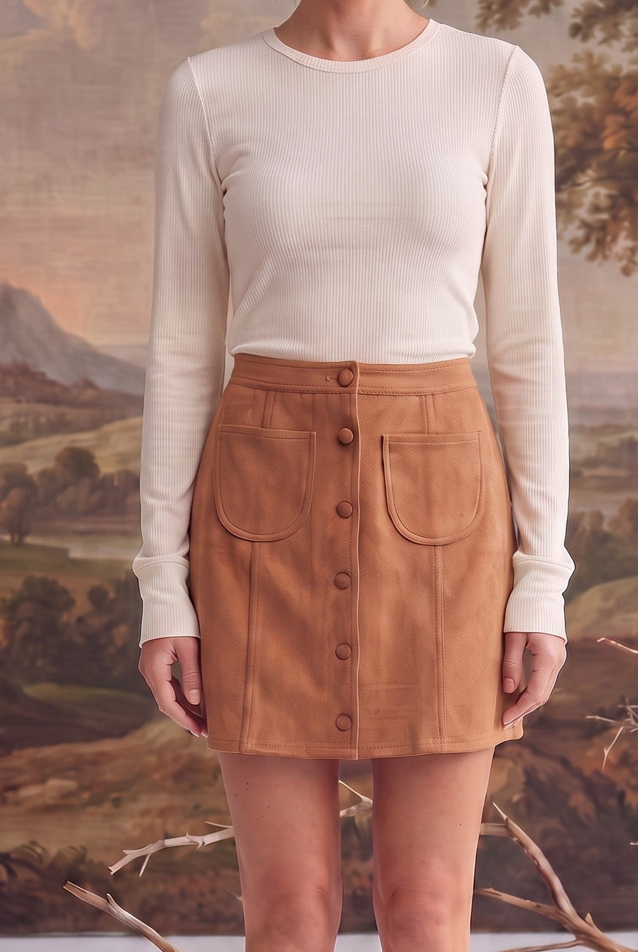 graced tan suede mini skirt with a button-front closure and two front patch pockets worn with a cream ribbed top