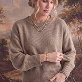 graced Eloise taupe crew neck sweater with dropped shoulders and ribbed cuffs worn by a woman with gold jewelry