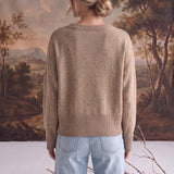 Back view of a woman wearing a graced taupe crew neck sweater with ribbed hem and cuffs, styled with light blue jeans.