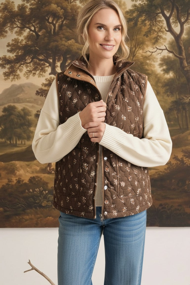 graced The Teagan Quilted Vest in brown with a floral pattern, worn over a cream sweater and blue jeans.