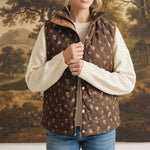 graced The Teagan Quilted Vest in brown with a floral pattern, worn over a cream sweater and blue jeans.