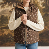 graced The Teagan Quilted Vest in brown with a floral pattern, worn over a cream sweater and blue jeans.