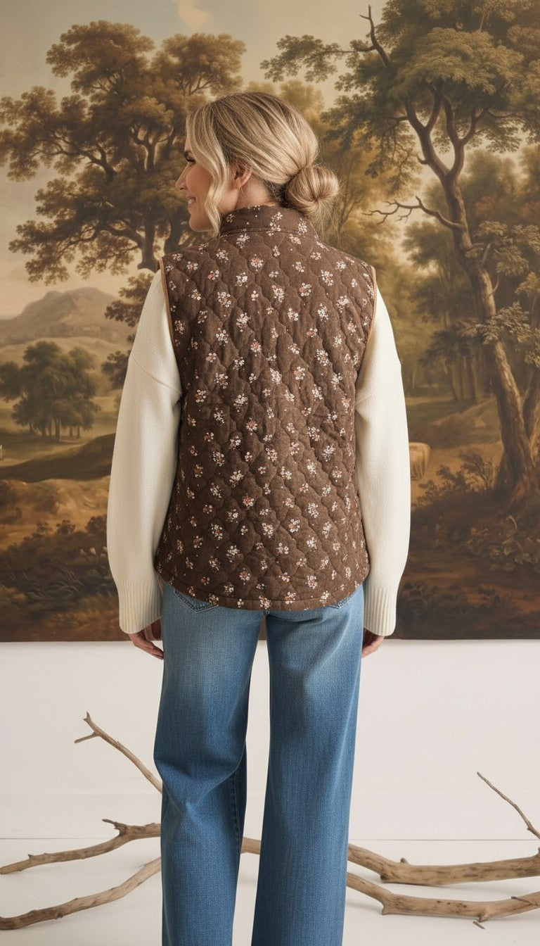 graced The Teagan Quilted Vest in brown with a floral pattern, worn over a cream sweater and blue jeans, back view