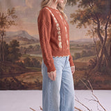 graced terracotta cable knit sweater with floral embroidery worn by a blonde model with light wash wide leg jeans