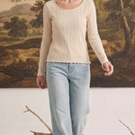 graced textured ribbed long sleeve top in beige worn by a woman with light blue jeans in a studio setting