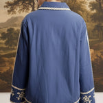 Back view of a woman wearing the blue graced The Lea Embroidered Lace Jacket with white floral embroidery details.
