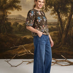 graced washed dark denim tie-front pants with a relaxed wide-leg fit worn by a smiling woman in a studio setting