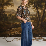 graced washed dark denim tie-front pants with a relaxed wide-leg fit worn by a smiling woman in a studio setting