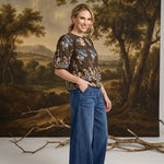 graced washed dark denim tie front pants with a relaxed wide-leg fit worn by a smiling woman in a floral top