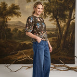 graced washed dark denim tie front pants with a relaxed wide-leg fit worn by a smiling woman in a floral top