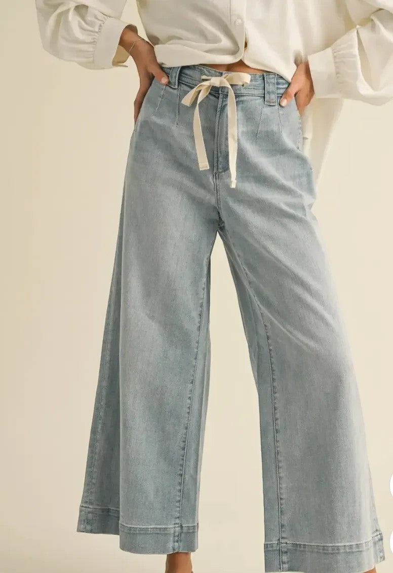 graced washed denim pants with a tie-front waist and relaxed wide-leg fit worn with a white blouse