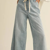 graced washed denim pants with a tie-front waist and relaxed wide-leg fit worn with a white blouse