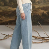 graced washed denim tie-front pants in light blue worn by a blonde model with a cream sweater and neutral heels
