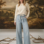 graced washed denim tie-front pants in light blue with a relaxed wide-leg fit worn by a model with a cream sweater
