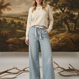 graced washed denim tie-front pants in light blue with a relaxed wide-leg fit worn by a model with a cream sweater