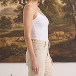 Model wearing graced white fitted nylon-spandex cami with spaghetti straps, side profile view.