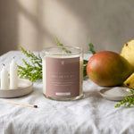 Candle with a label on a table with fruit and small candles