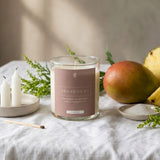 Candle with a label on a table with fruit and small candles