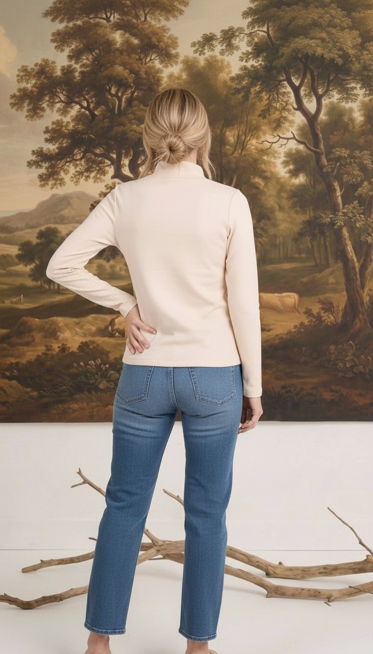 graced ivory knit long sleeve mock neck top worn by a woman with blonde hair in a bun, back view
