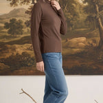 Woman wearing a mocha brown graced long sleeve mock neck knit top with blue jeans and beige flats