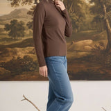 Woman wearing a mocha brown graced long sleeve mock neck knit top with blue jeans and beige flats
