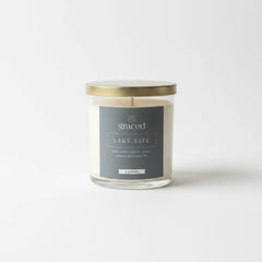 Graced Lake Life soy wax candle with a white jar and wooden lid, featuring a label with lake-inspired design and natural decor.