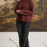 Model wearing a graced maroon ribbed cuff sweater with a relaxed fit, paired with black jeans in a studio setting.