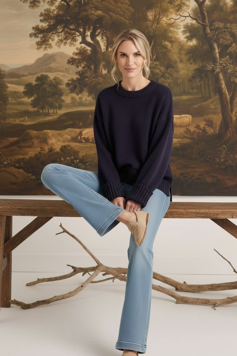 graced navy ribbed cuff sweater worn by a woman with light blue jeans and beige loafers in a rustic setting