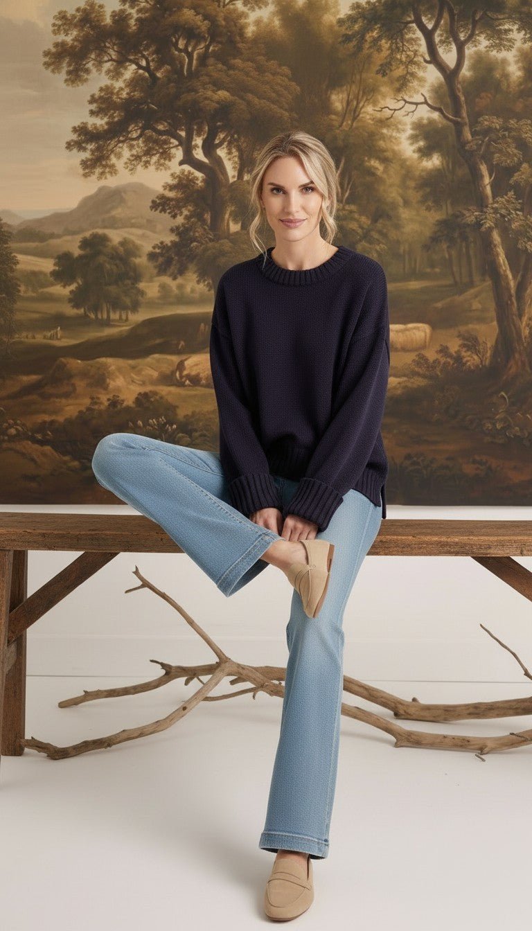 graced navy ribbed cuff sweater worn by a woman with light blue jeans and beige loafers in a rustic setting