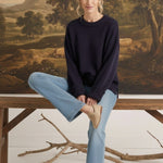 graced navy ribbed cuff sweater worn by a woman with light blue jeans and beige loafers in a rustic setting